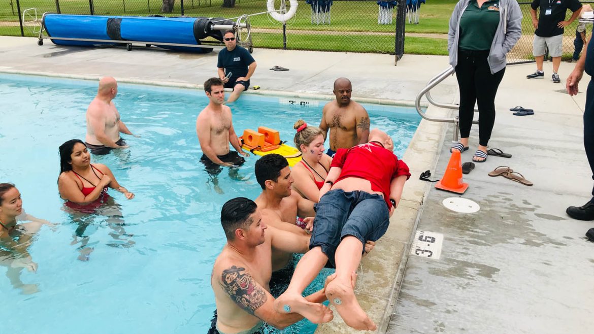 People lifting CPR dummy out of pool.