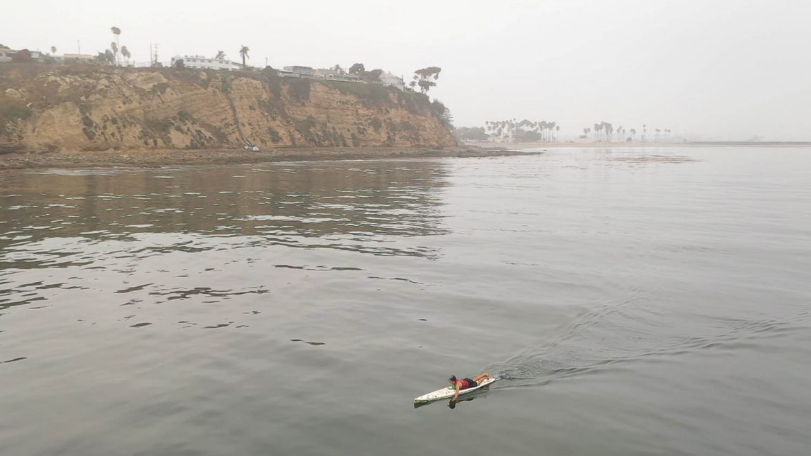 Zoomed out image of a lifeguard paddling.