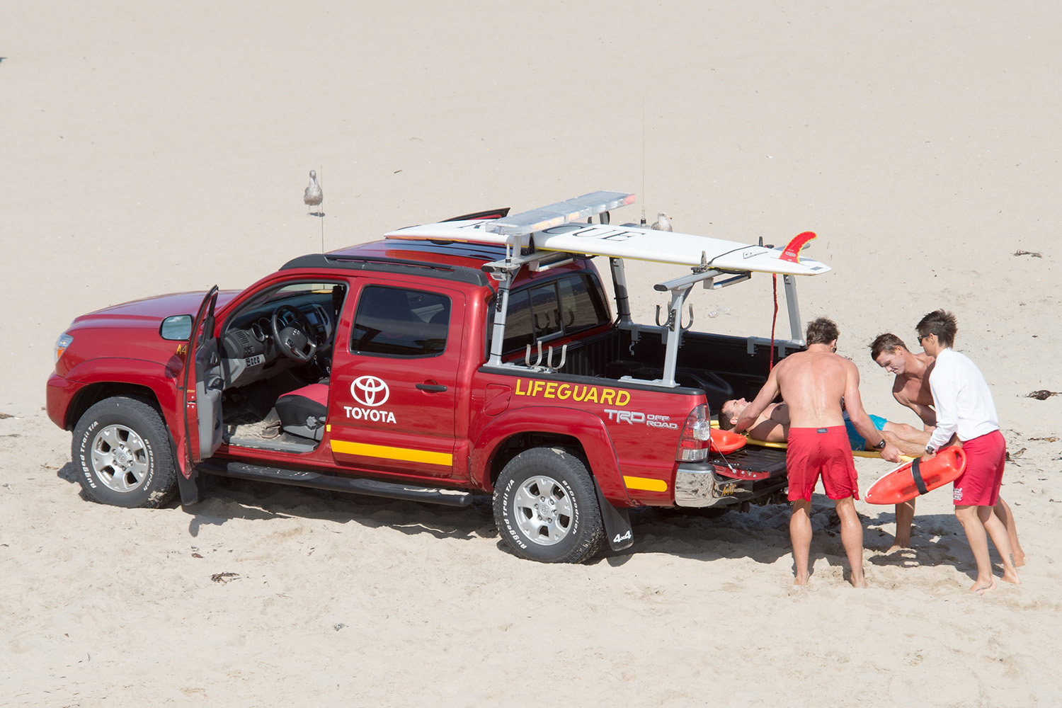 Lifeguards helping a patient into the back of a truck.