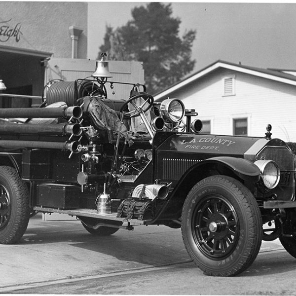 Historical fire engine with a fire station in the background.