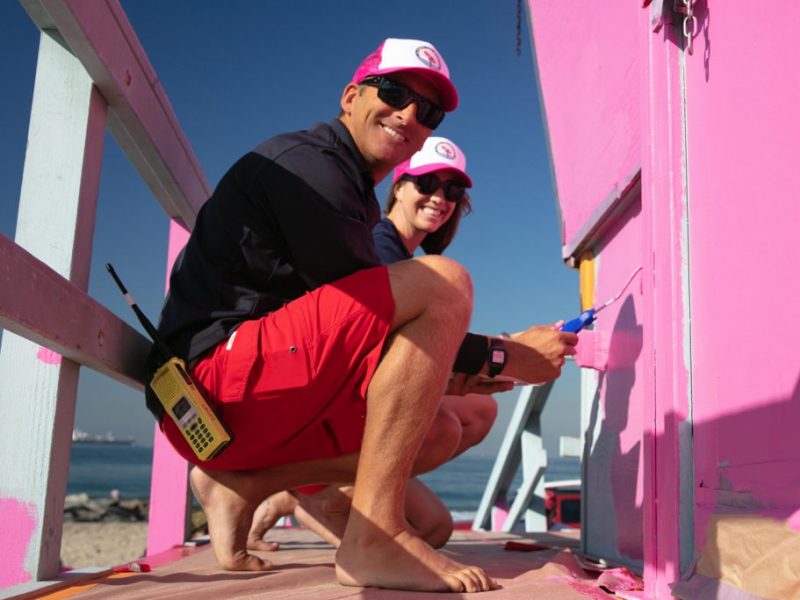 Two lifeguard staff painting tower pink