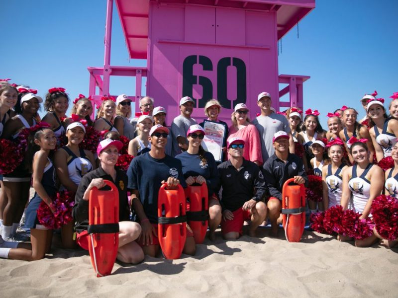 group of lifeguard staff in front of pink lifeguard tower 60