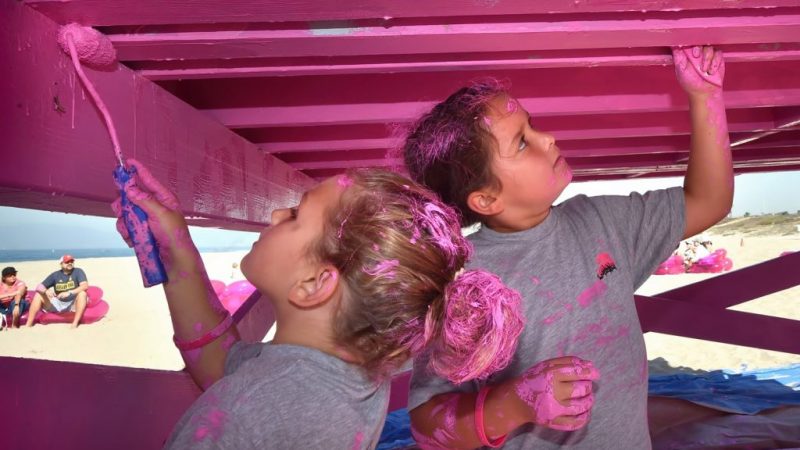 two children painting lifeguard tower pink.