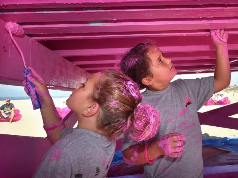 two children painting lifeguard tower pink.