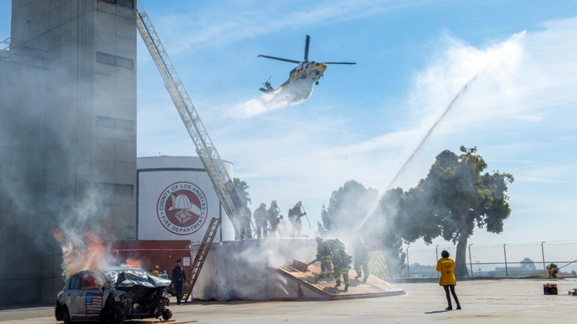 Training drill with firefighters and burning car with a helicopter